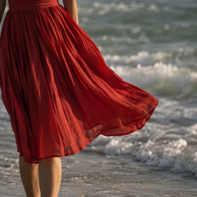 Close-up of scarlet dress pleats against muted green seawater